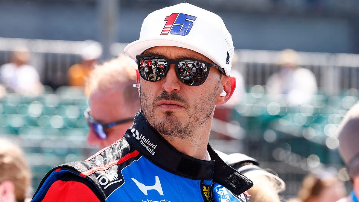 Graham Rahal stands on pit lane with his Honda race car at Indianapolis Motor Speedway.