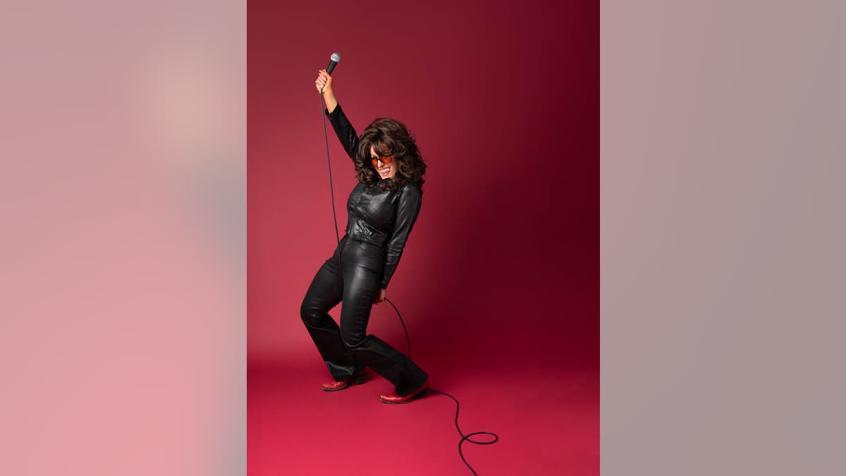Hannah Dasher in leather holding microphone 