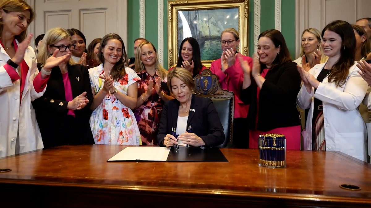 people clap as Gov. Healey signs bill