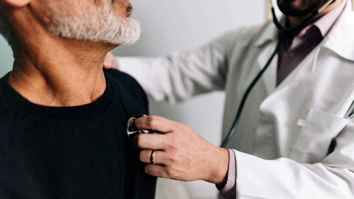 A doctor listens to a man's heart.