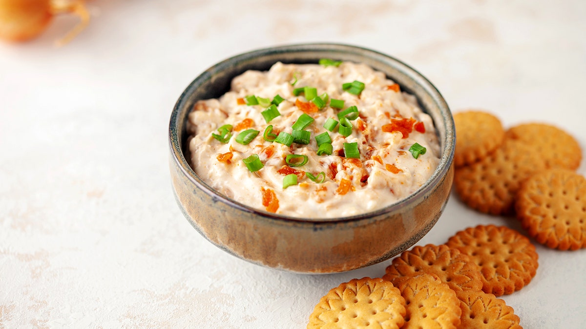 Homemade French onion dip in a bowl next to crackers.