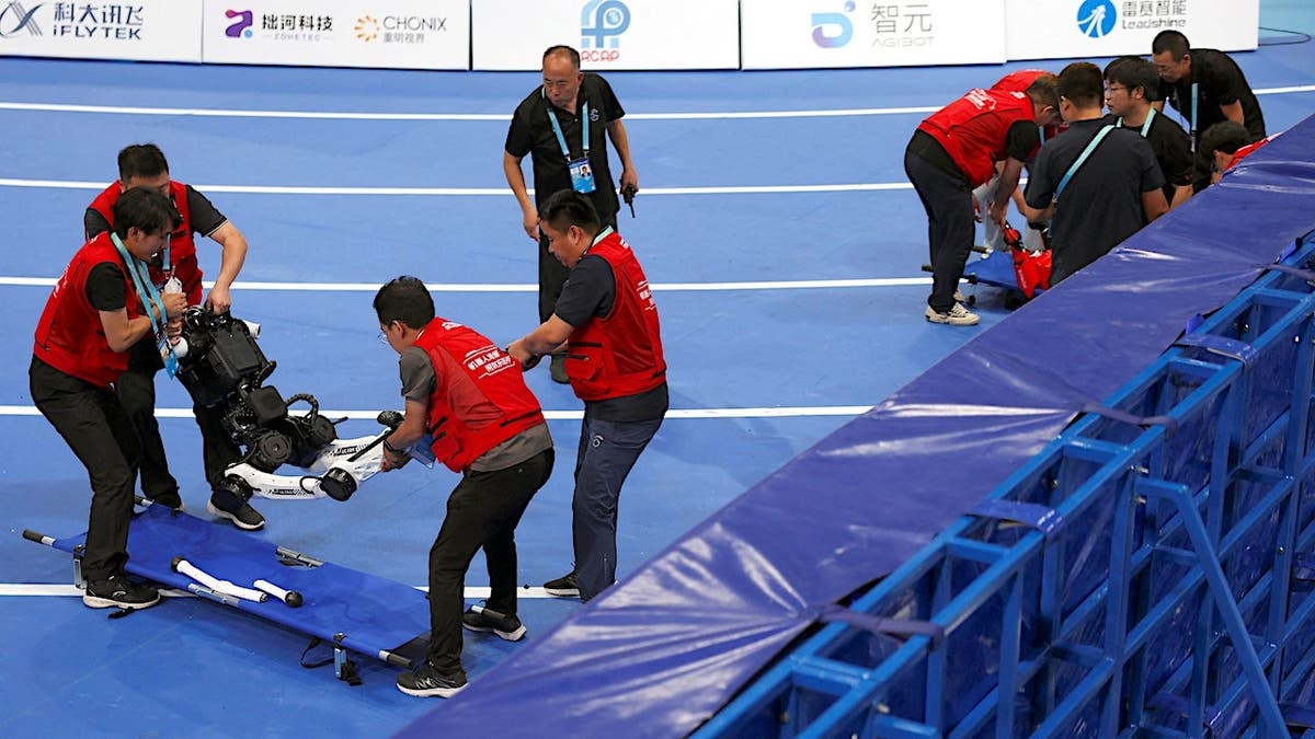 Staff members move a humanoid robot onto a stretcher after a race at the World Humanoid Robot Games in Beijing.