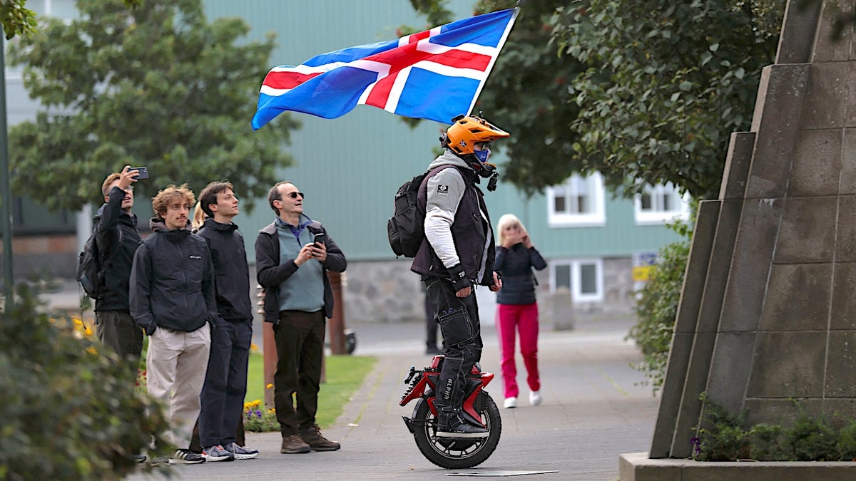 A man with an Icelandic flag rolls around in a park in Reykjavik, Iceland