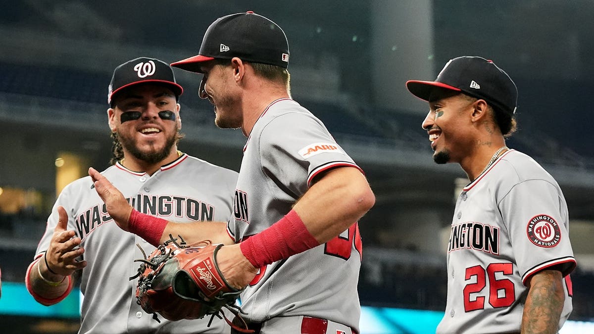 Jacob Young catches a fly ball and throws to second as Washington Nationals teammates gather nearby.