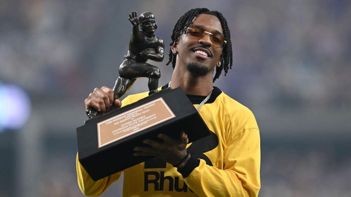 Jayden Daniels holds the Heisman Trophy at Allegiant Stadium.