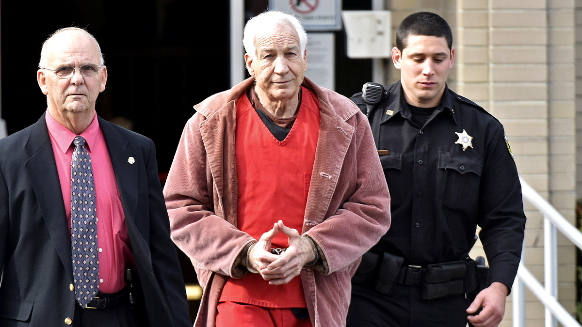 Jerry Sandusky in handcuffs and a prison jumpsuit escorted out of court