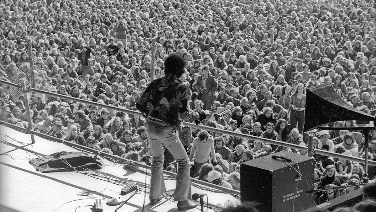 Jimi Hendrix performs onstage with a Fender Stratocaster guitar.