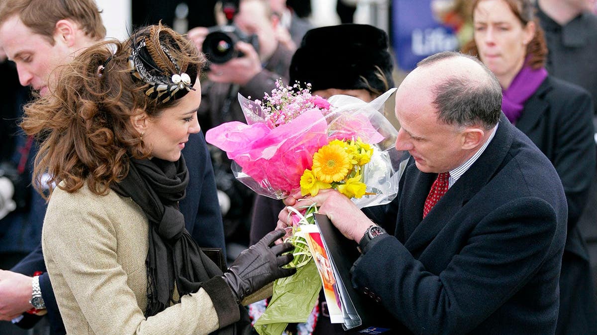 Kate Middleton hands Jamie Lowther-Pinkerton bunches of flowers during a walkabout.