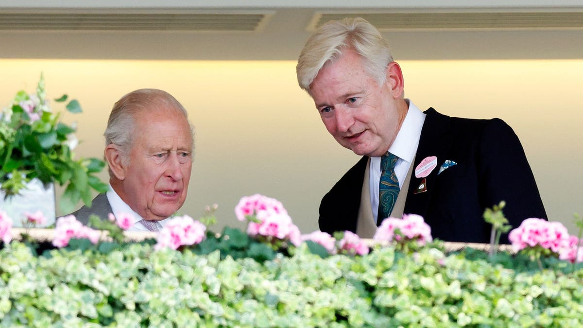 King Charles III and Sir Clive Alderton watch racing from the Royal Box at Royal Ascot.