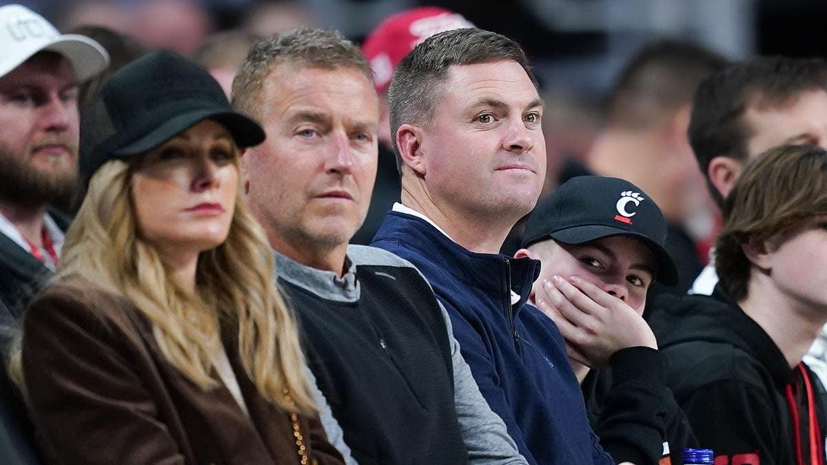 Kirk Herbstreit and Zac Taylor look on during a game at Fifth Third Arena in Cincinnati.