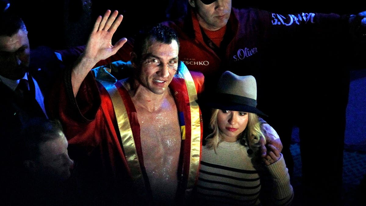 Wladimir Klitschko waves to fans beside Hayden Panettiere after a boxing match.