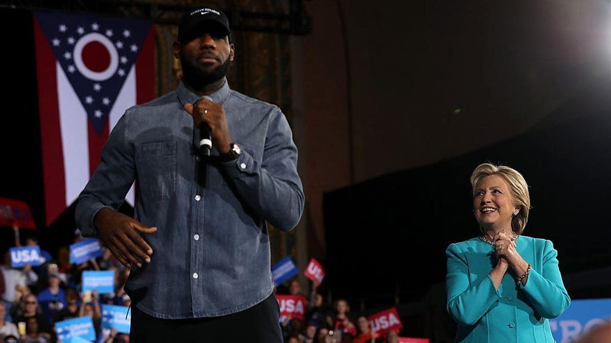 LeBron James speaks at a campaign rally as Hillary Clinton looks on.