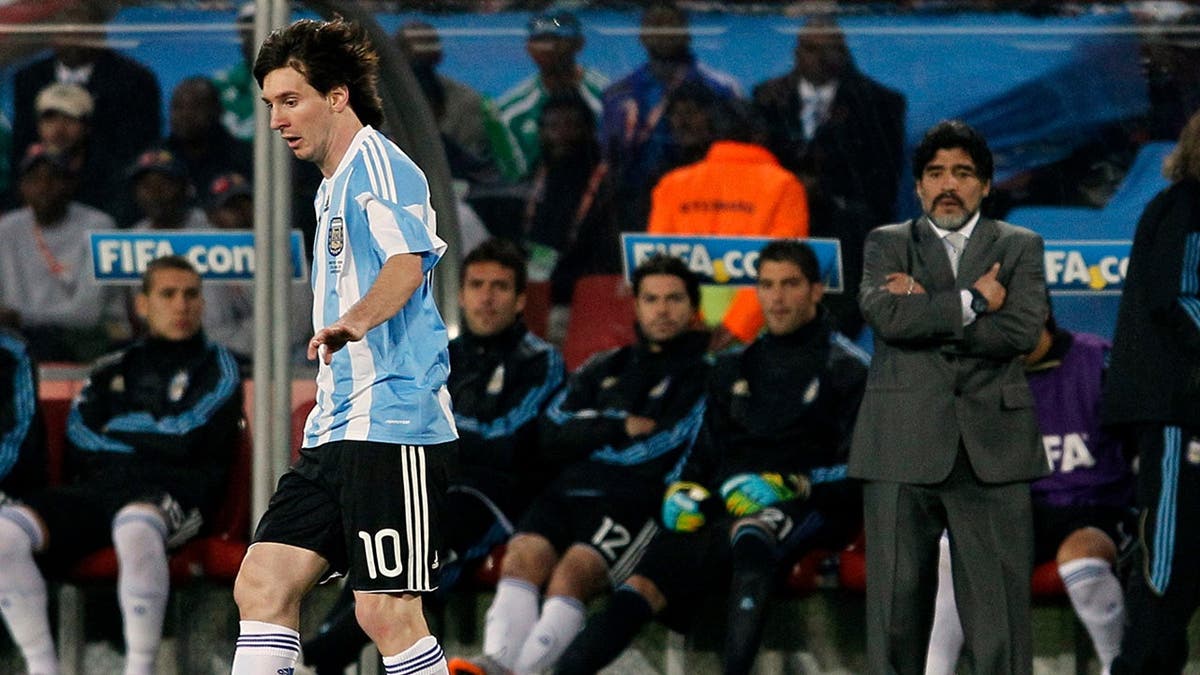 Lionel Messi controls the ball as Diego Maradona looks on during a World Cup soccer match.
