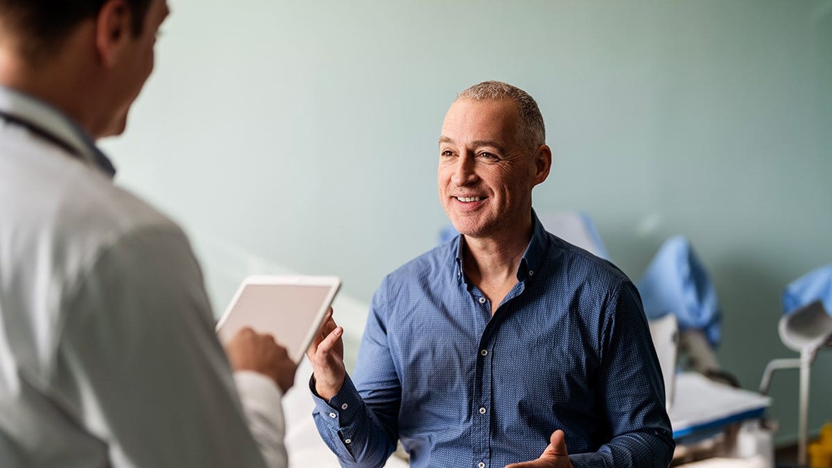 Doctor uses a digital tablet during a medical examination with a male patient.