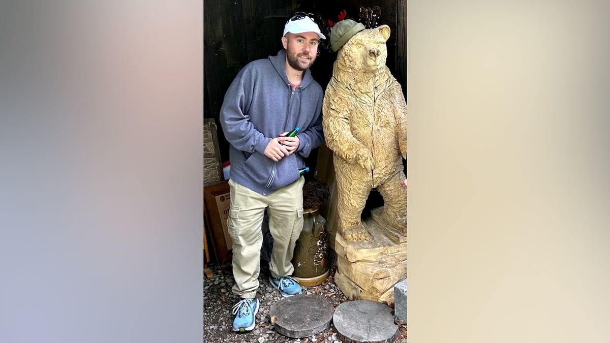 Marcin Bachleda-Blaszczak smiling and posing with bear statue