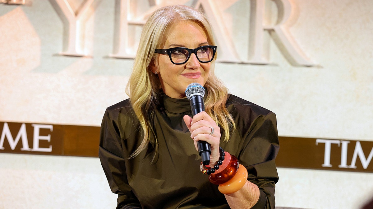 Mel Robbins holds a microphone.
