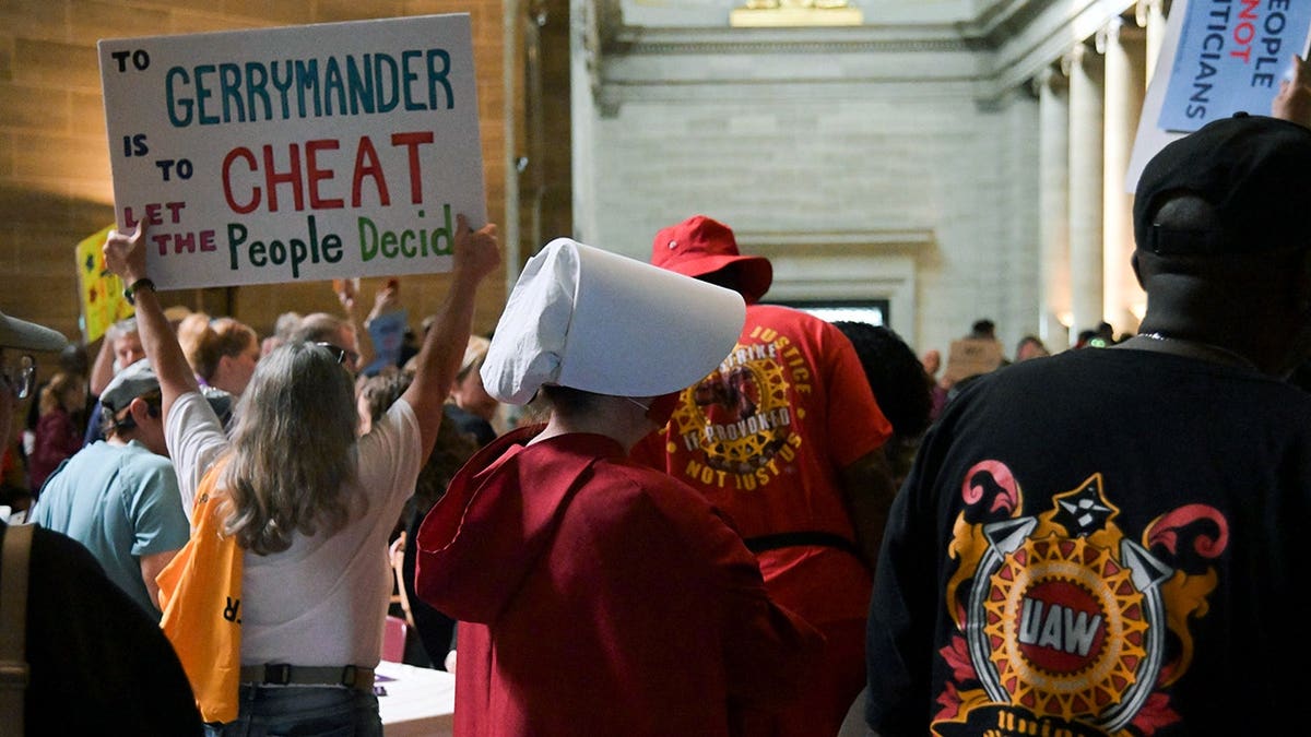 Woman in Handmaids Tale costume stands in Missouri Capitol rotunda during protest.