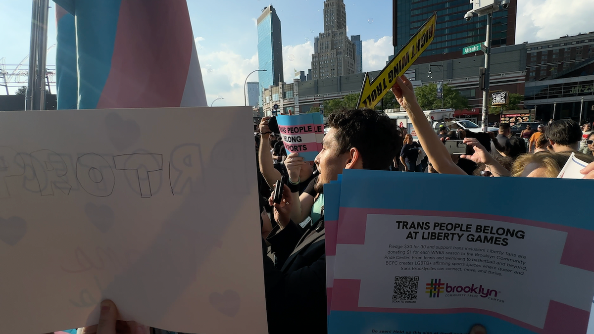 Pro-transgender protesters gather around a reporter