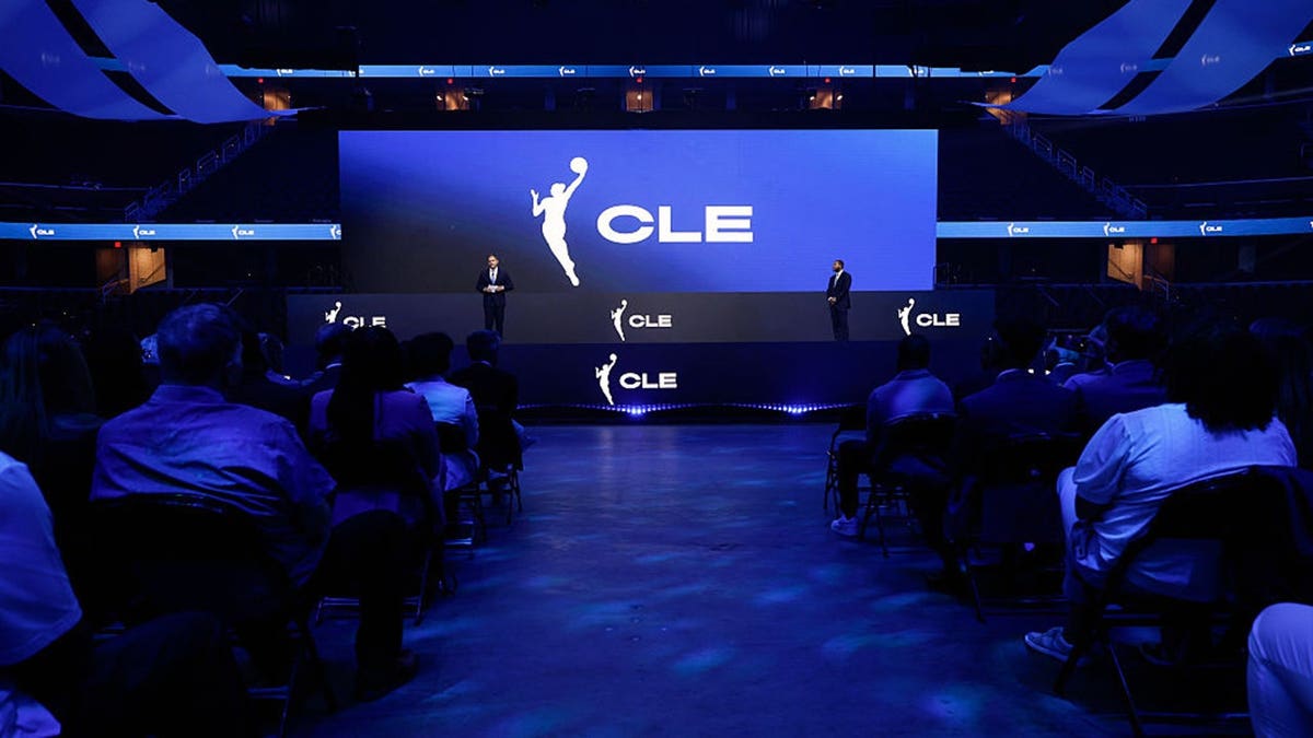 Nic Barlage and Koby Altman stand at Rocket Arena during a WNBA team name and logo reveal.