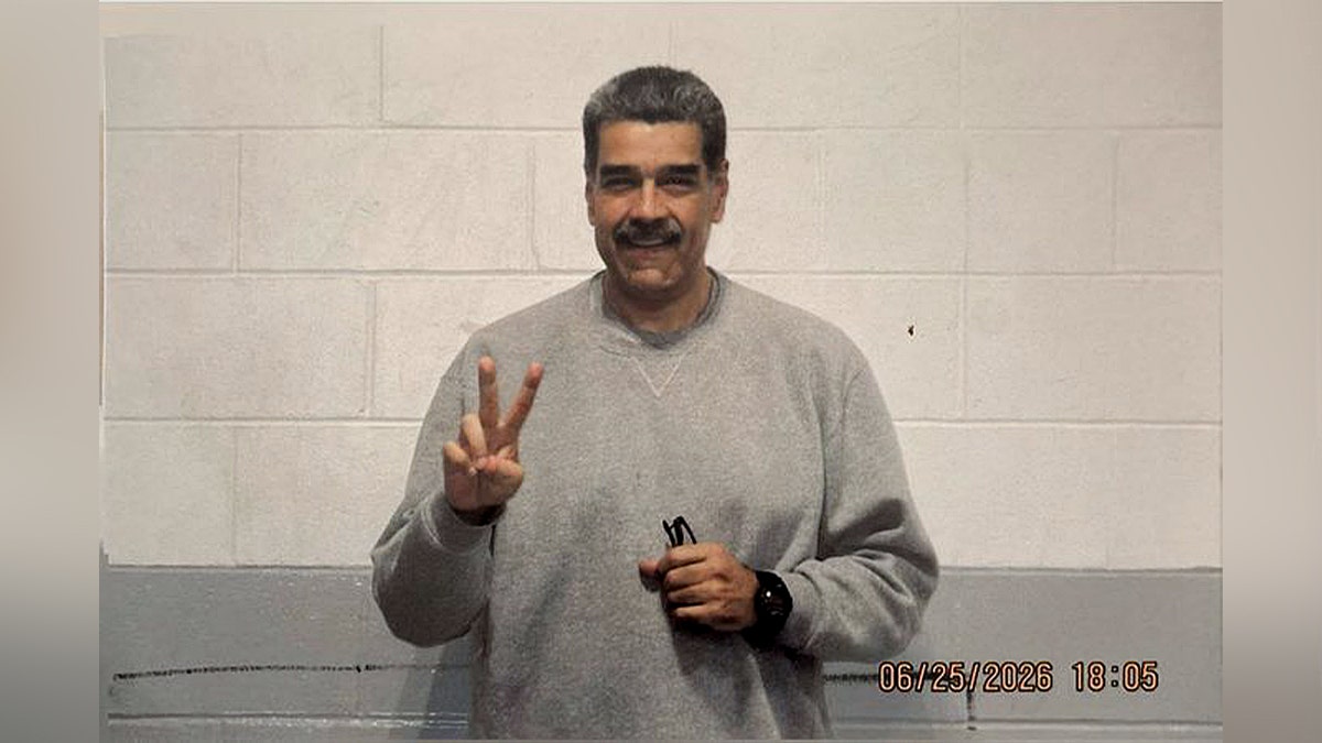 nicolas maduro in gray sweatsuit holding a peace sign and smiling