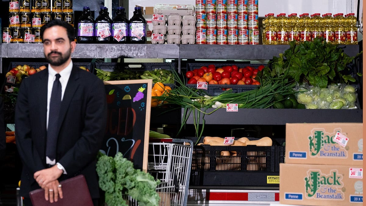 Zohran Mamdani, mayor of New York, stands behind groceries at a community food distribution center.