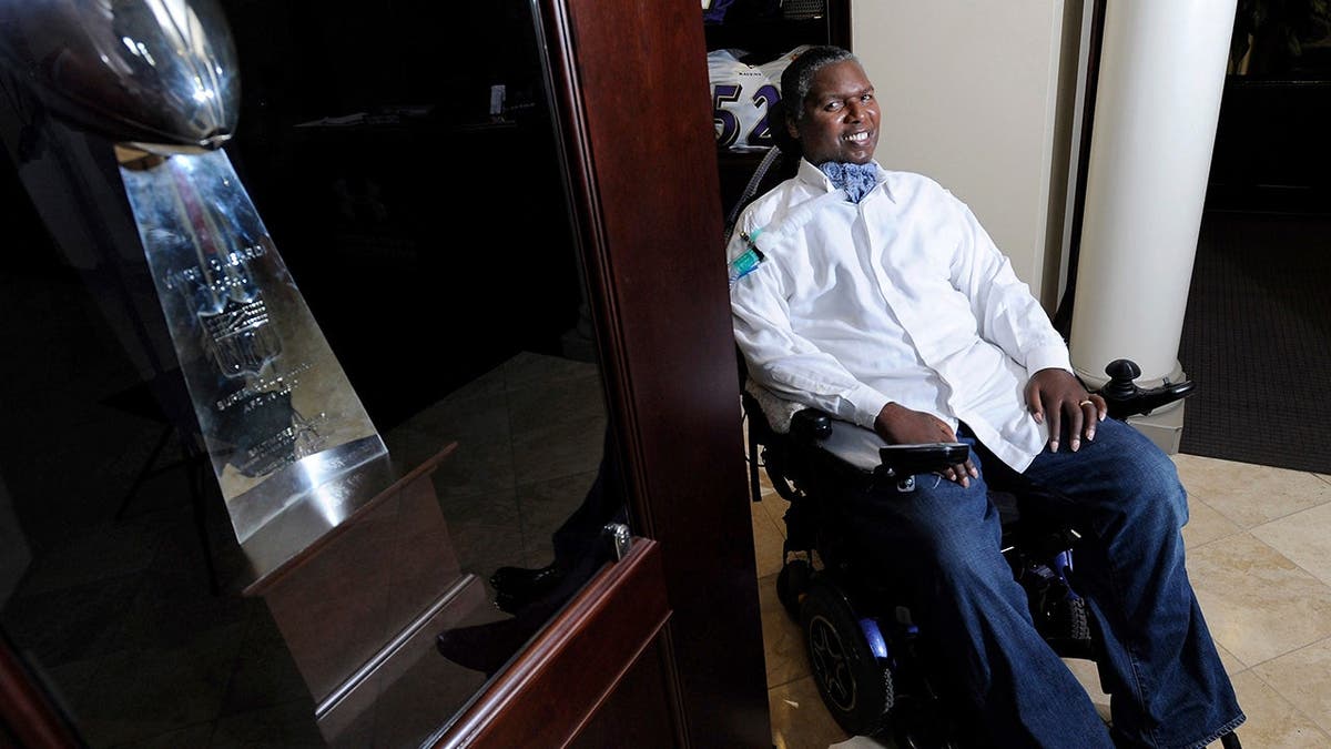 O.J. Brigance sits near the Vince Lombardi Trophy at the Ravens practice facility.