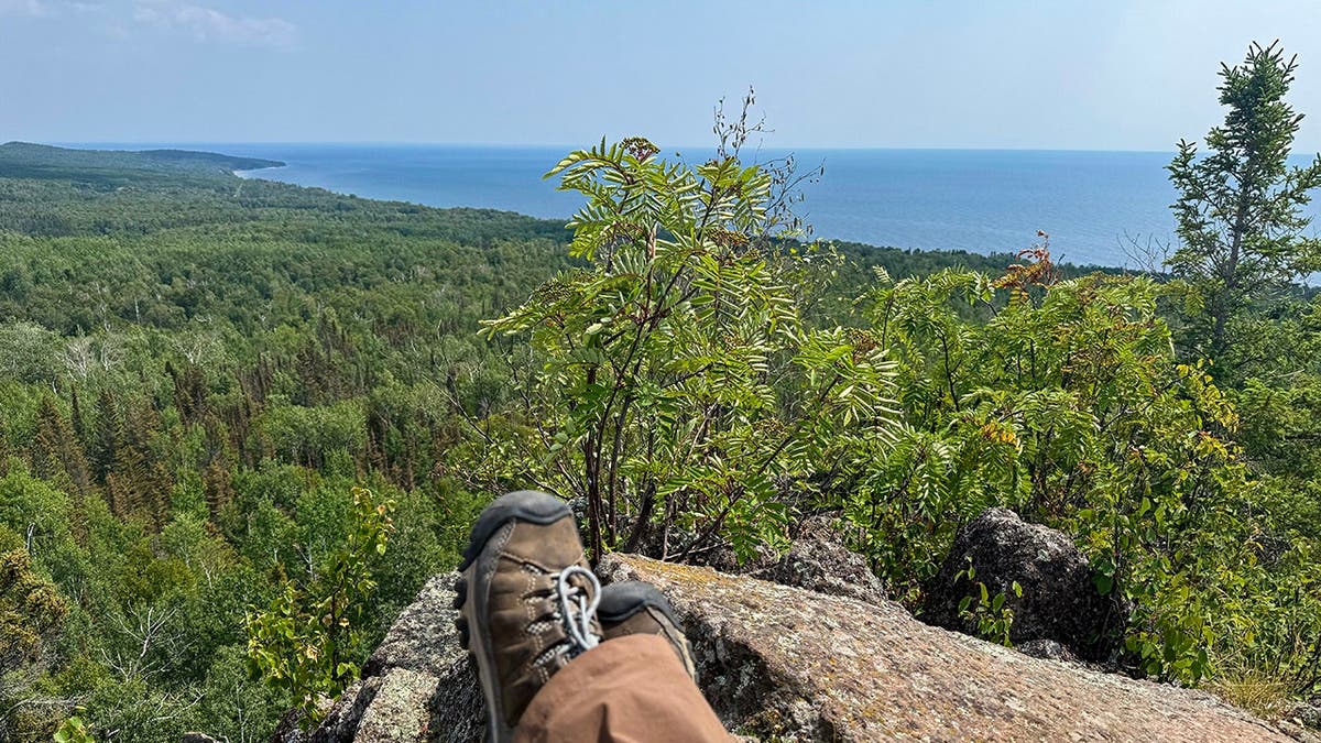 two hiking boots above a view of woods and lake superior