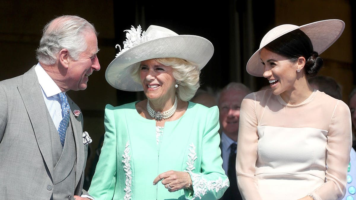 Prince Charles, Camilla and Meghan stand together at Buckingham Palace.