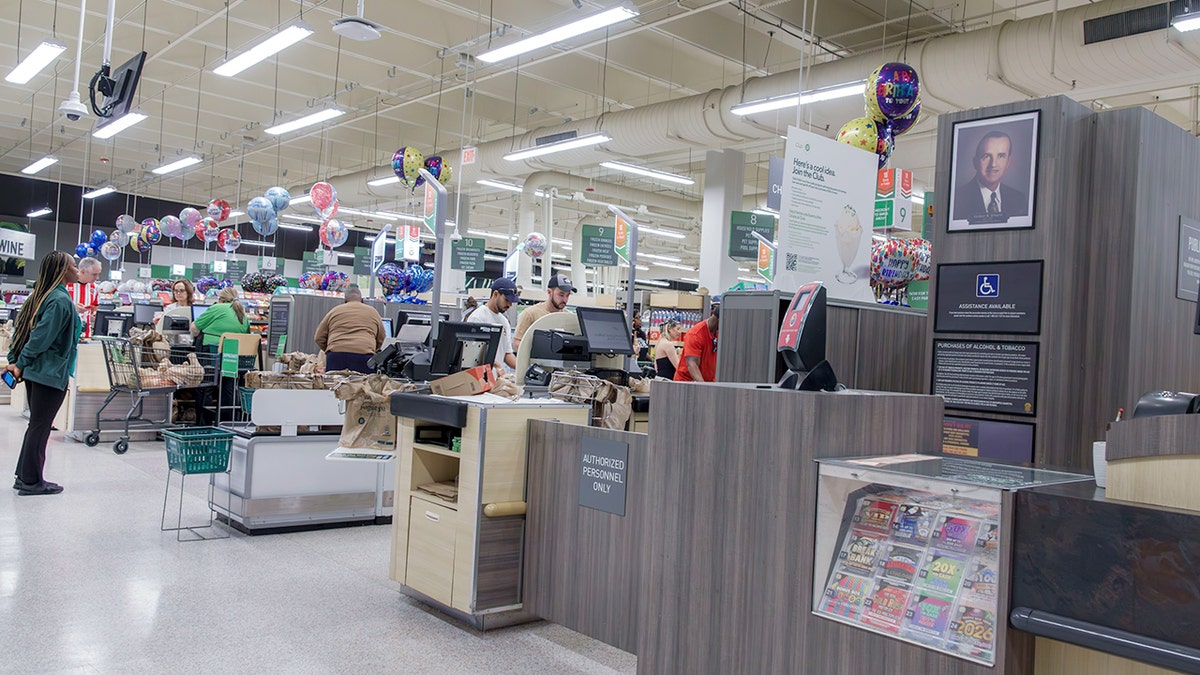 A Publix employee stands and looks at the checkout lanes.