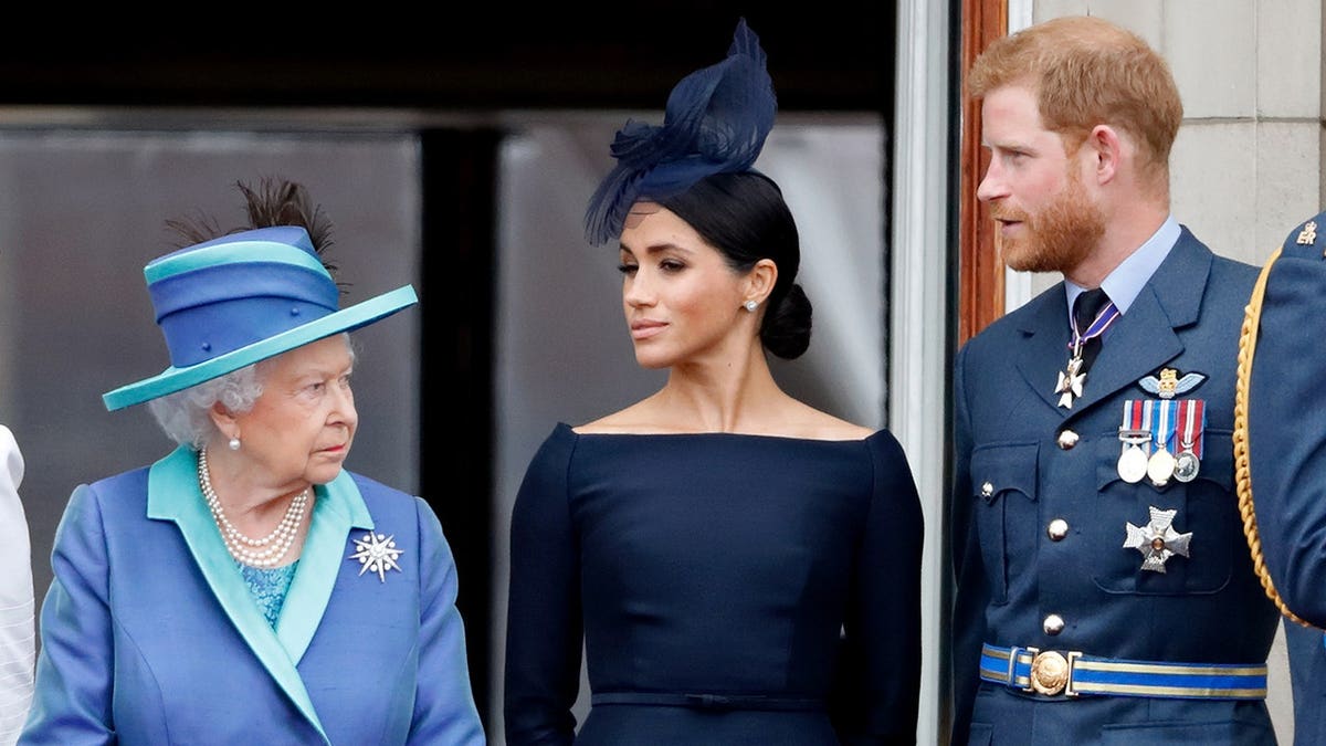 Queen Elizabeth II, Meghan Duchess of Sussex and Prince Harry watch a Royal Air Force flypast from Buckingham Palace balcony.