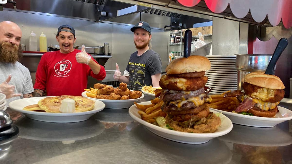 Some cooks at the Red Arrow Diner pose for a photo in front of some food.