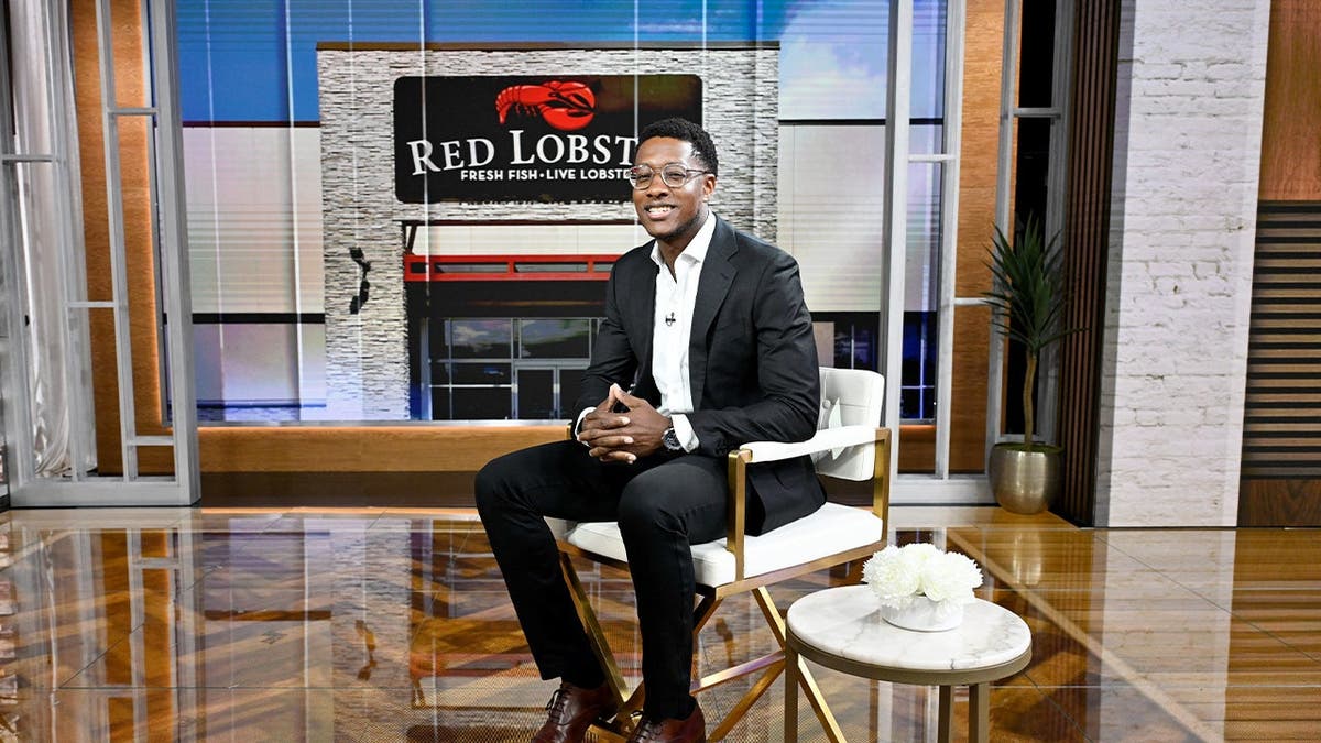 Red Lobster CEO Damola Adamolekun sits on a stool.
