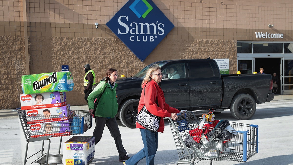 People walking outside of a Sam's Club with carts of baby supplies.