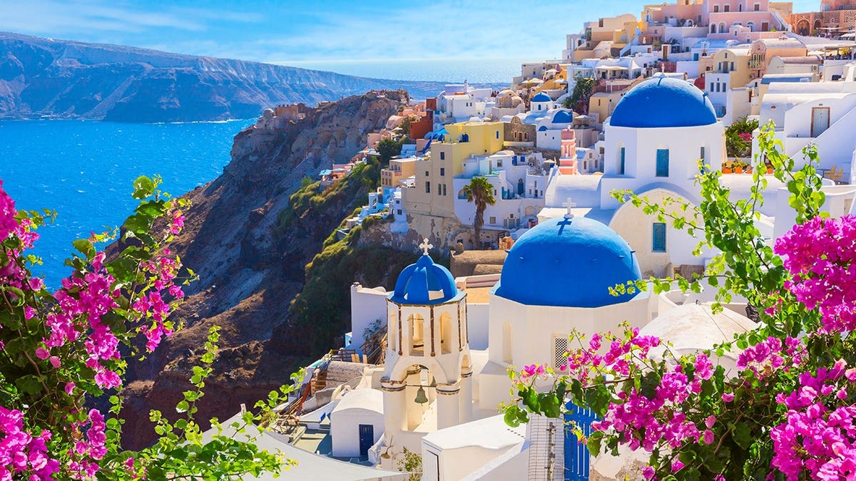 White houses and blue-domed churches overlook the caldera in Oia, Santorini, Greece.