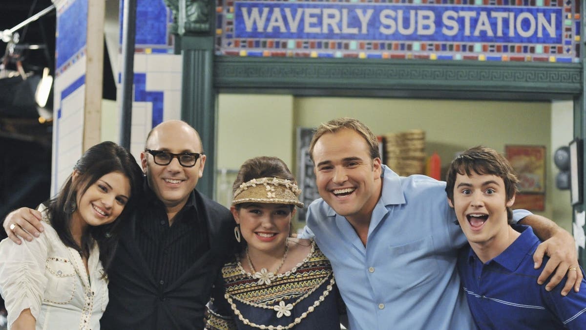 Selena Gomez, Willie Garson, Jennifer Stone, David DeLuise and Dan Benson stand together on a set.