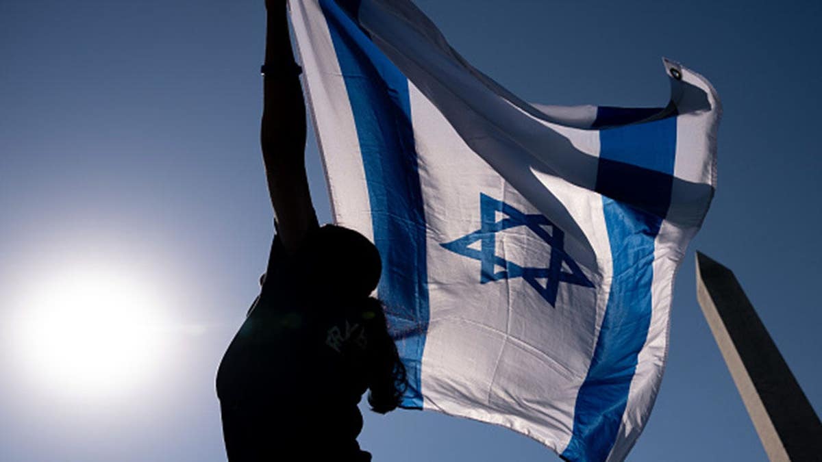 Sherry Colvin of Arlington, Va., holds an Israeli flag while praying and dancing near the Washington Monument.