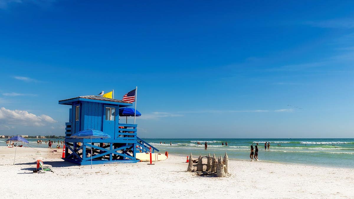 Lifeguard hut stands on Siesta Key Beach with ocean and blue sky in the background.