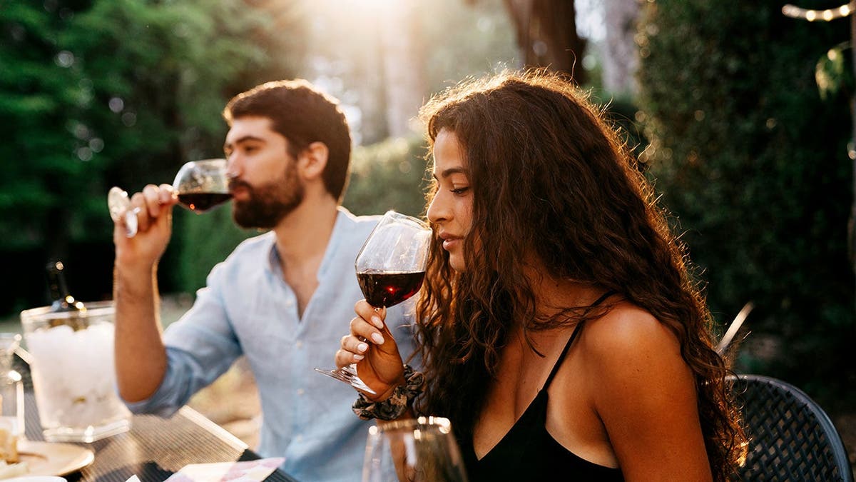 Two people taste wine.