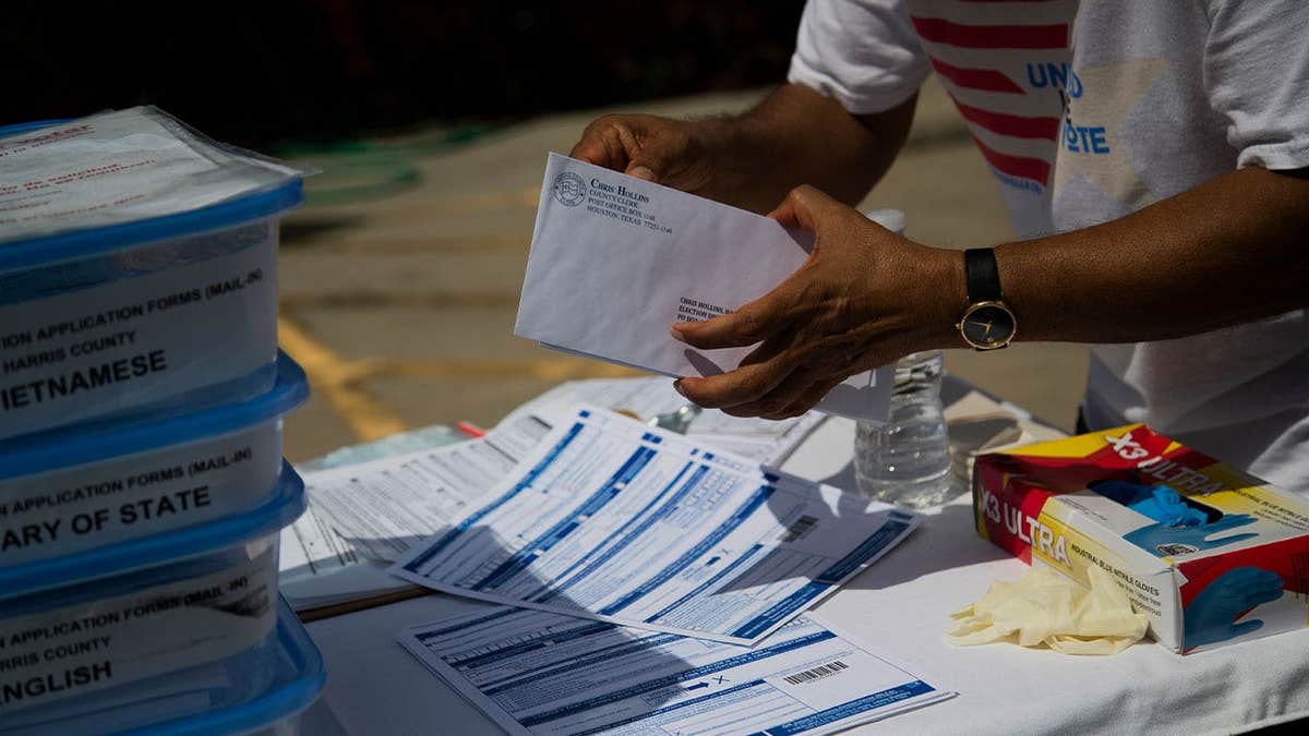 Harris County voter registrar Muhammed Nasrullah holds mail-in voting applications at a Houston food distribution event.