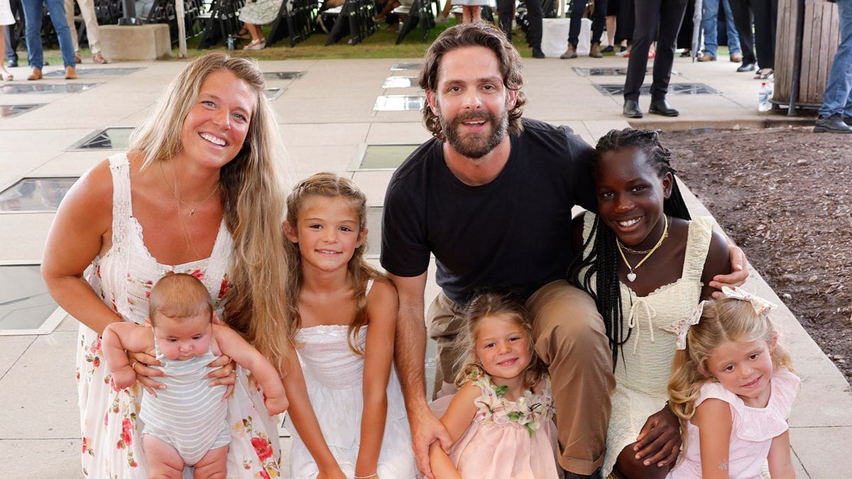 Lauren Akins and Thomas Rhett pose with their children at an induction ceremony.