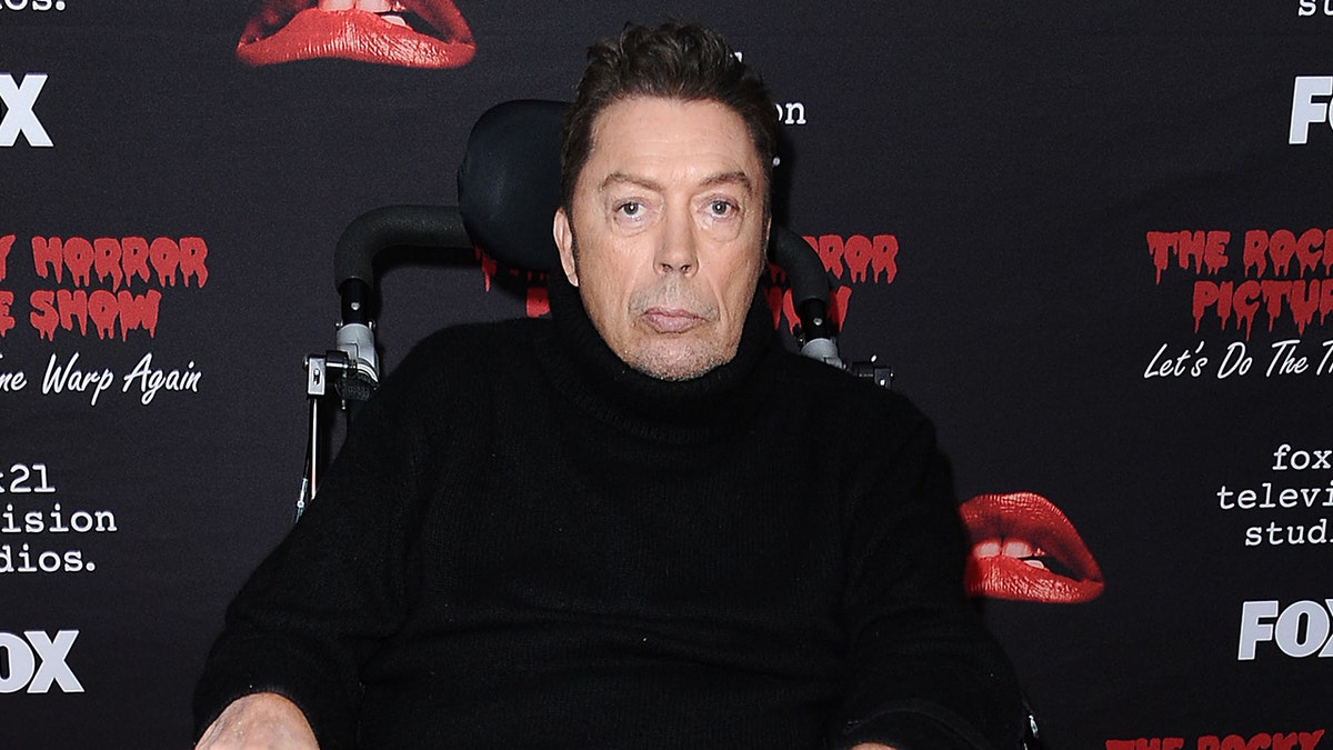 Tim Curry on the red carpet of a premiere for "The Rocky Horror Picture Show". He is seen in a wheel chair.