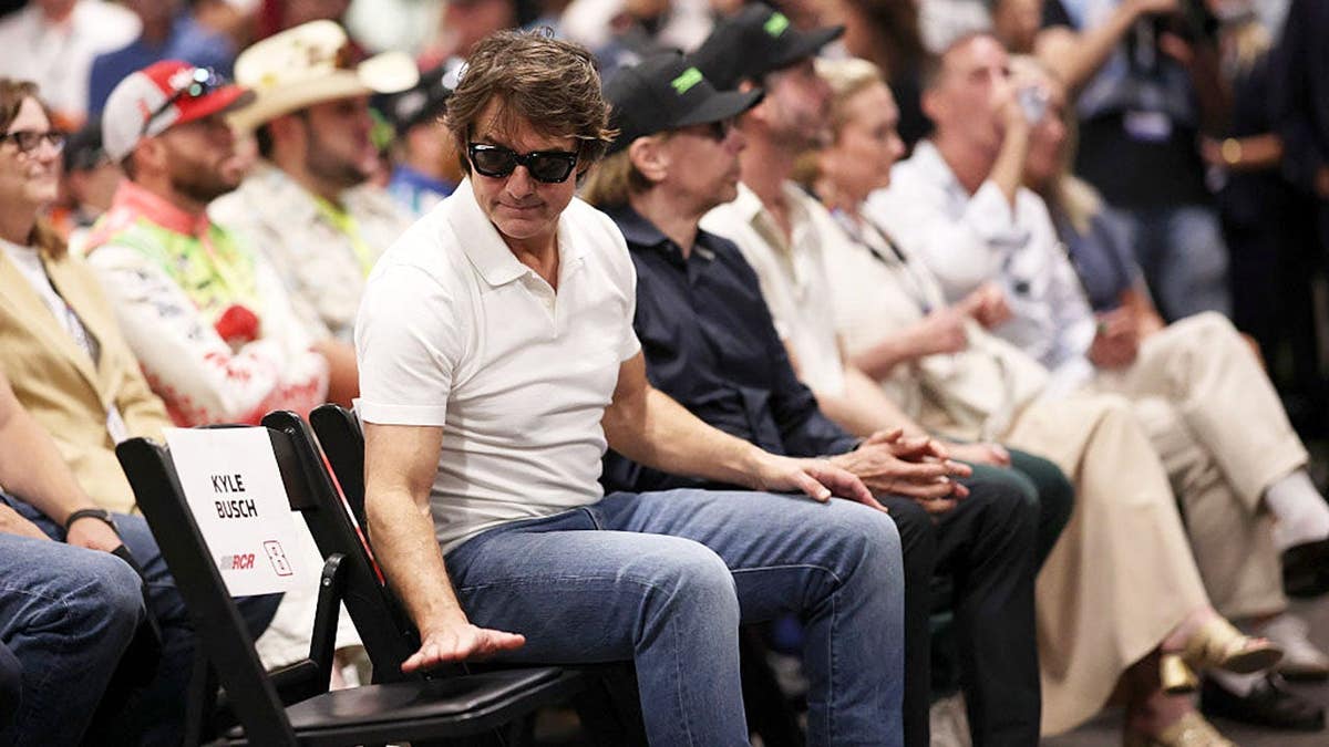 Tom Cruise stands near an empty chair during a drivers meeting at Daytona International Speedway.