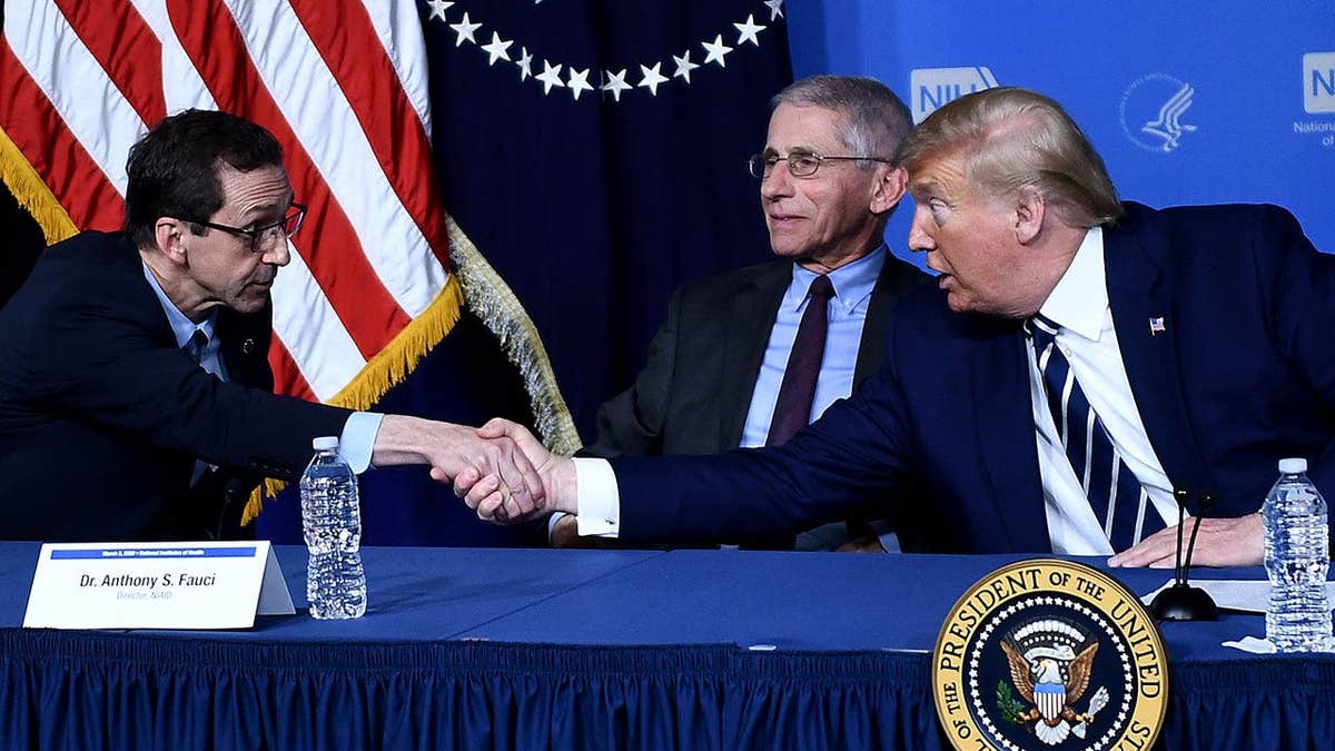 Donald Trump shakes hands with John Mascola as Anthony Fauci looks on.