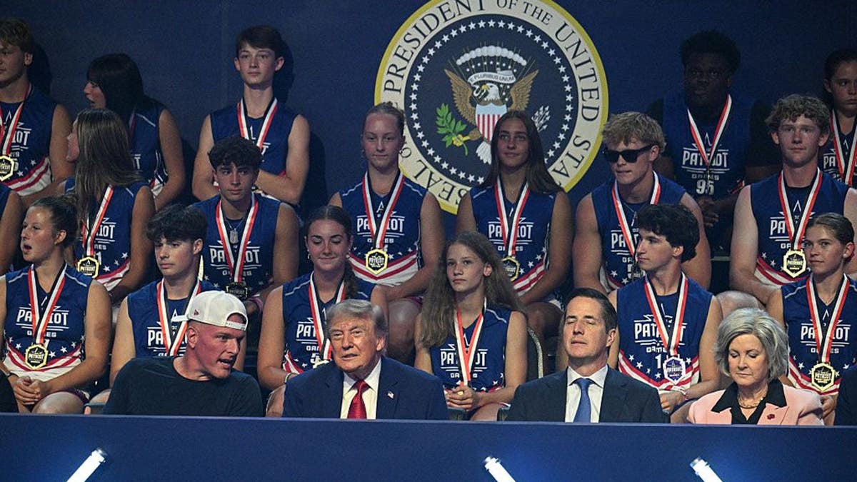 President Donald Trump stands with Pat McAfee and Susie Wiles at the Patriot Games finals.