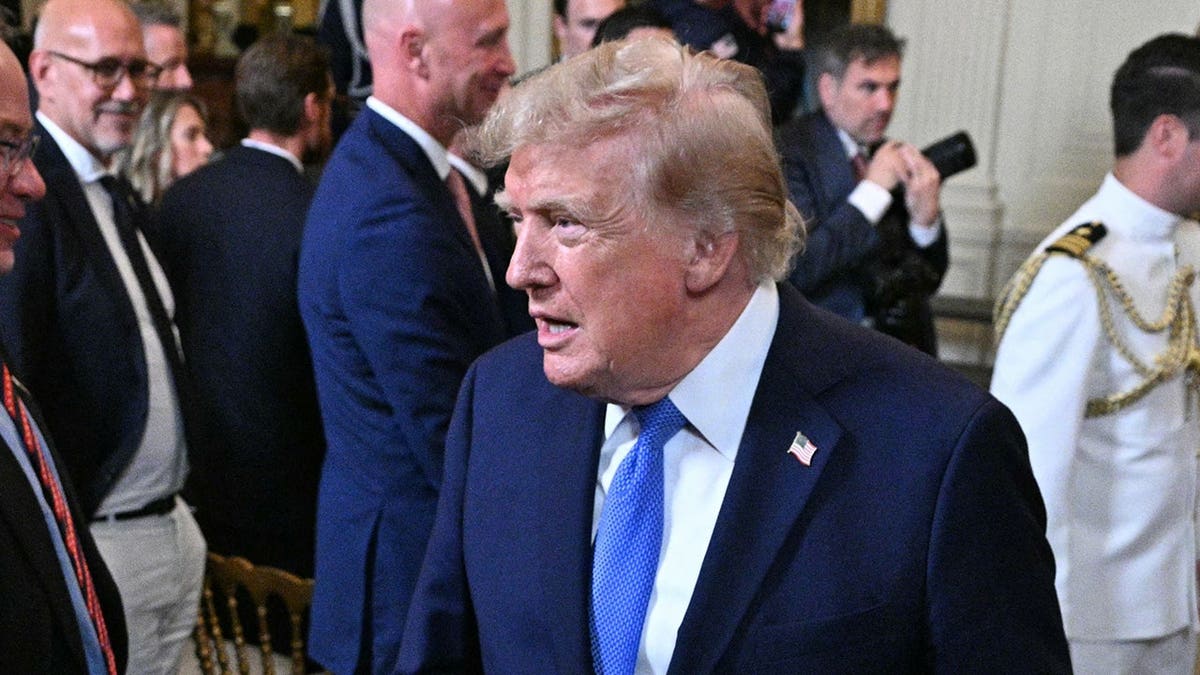 President Donald Trump holds shoes and a jacket gifted by Team USA in the East Room of the White House.