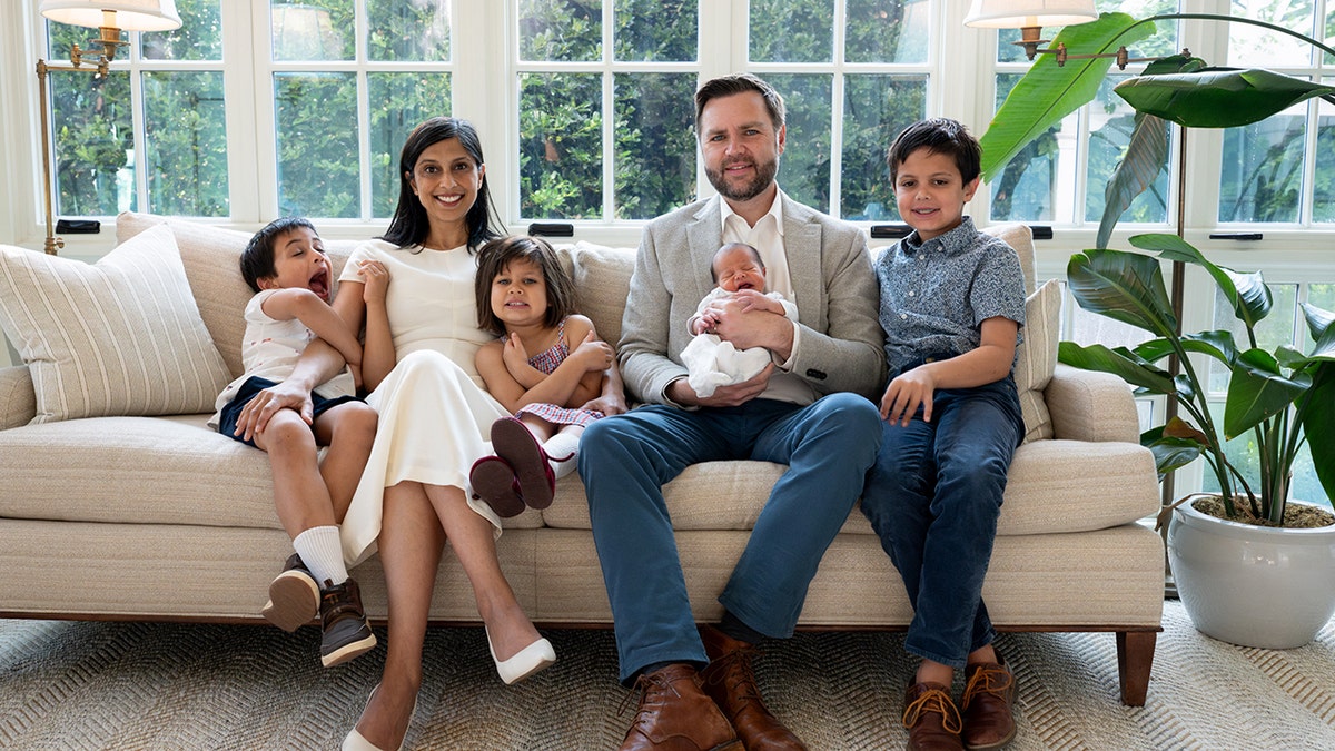 The Vance family with their children sitting on a couch in their home.