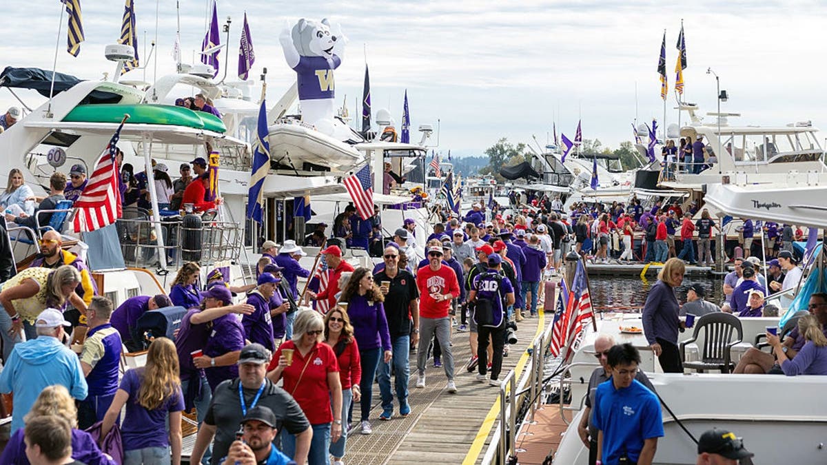 Washington Huskies fans tailgate on boats in a marina before a game.