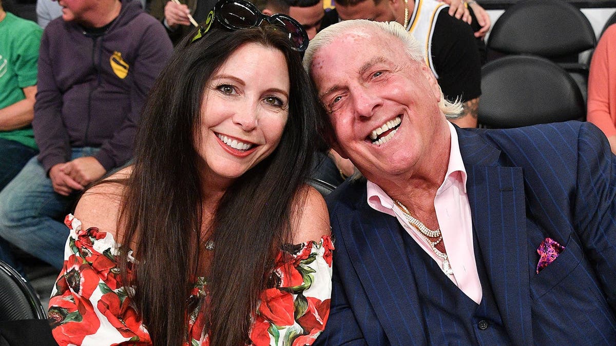Wendy Barlow and Ric Flair seated courtside at a basketball game.