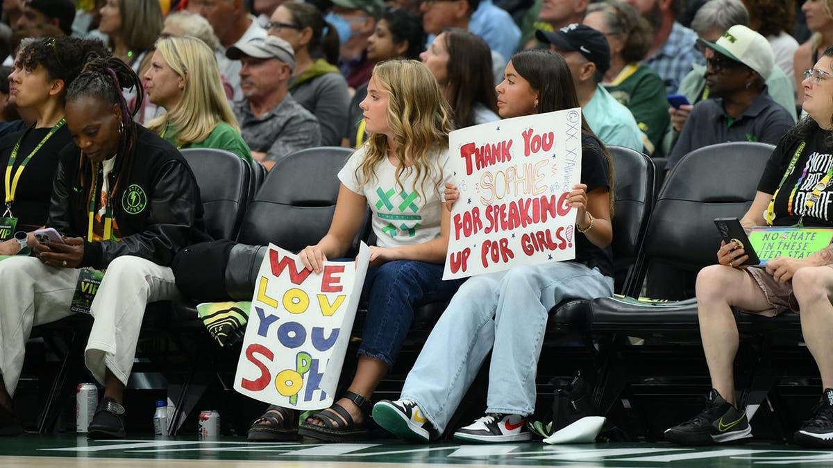 Fans hold a Sophie Cunningham sign during a WNBA game at Climate Pledge Arena.