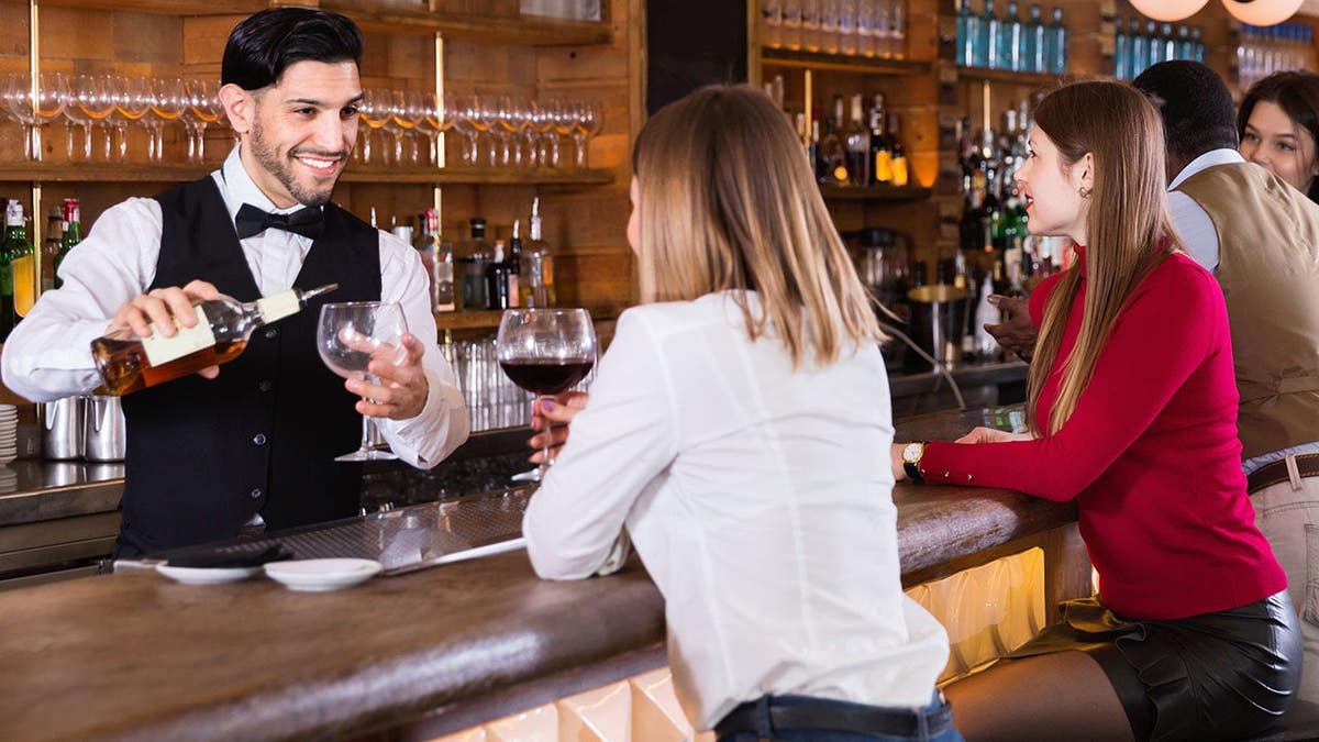 Portrait of barman and people who are standing near bar counter in luxurious restaurant